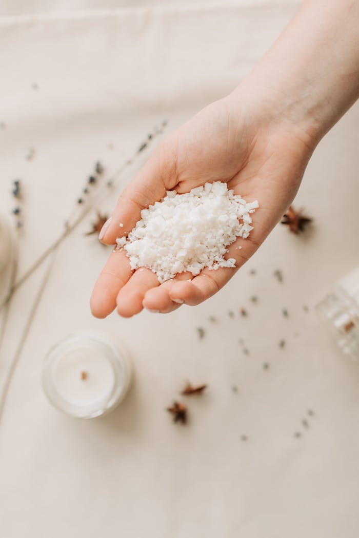 Hand holding natural bath salts with candle, promoting relaxation and calm. Perfect for spa themes.