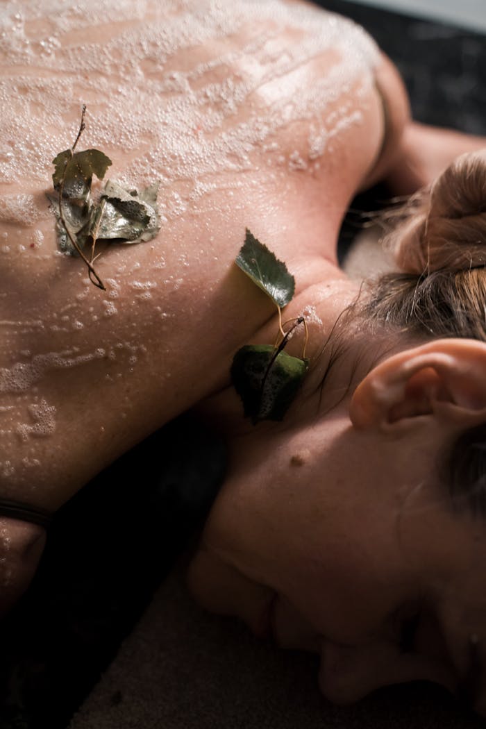 Close-up of a woman enjoying a relaxing spa treatment with natural leaves and exfoliation.